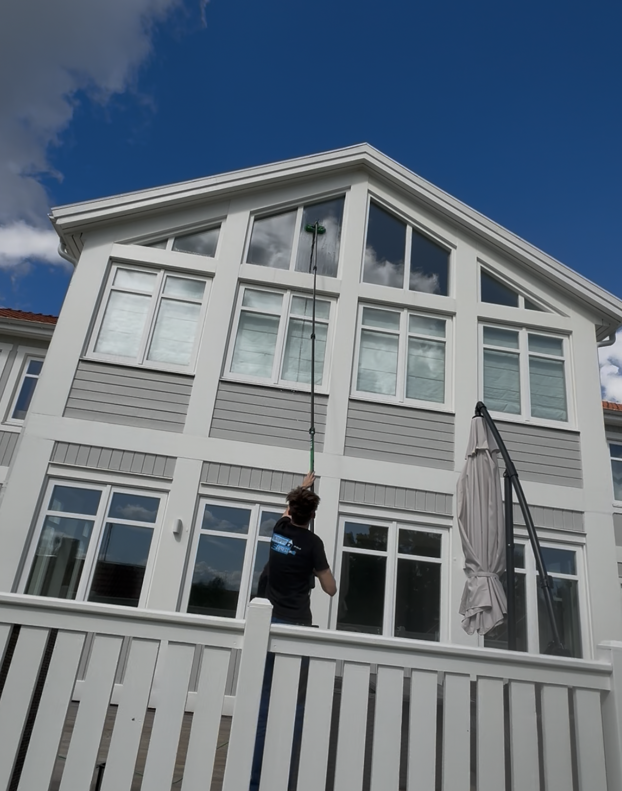 Tvättar fönster med renvattenfilter utvändigt på en villa